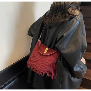 Détail du sac seau bordeaux en suédine avec longues franges et fermoir rotatif bronze