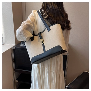 Detail of canvas tote with leather trim and gold buckle shown on a model's shoulder