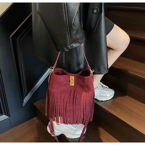Détail du sac seau bordeaux en daim avec franges longues et fermoir doré chic
