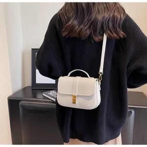Detailed back view of a woman wearing a cream crossbody square bag with a gold clasp
