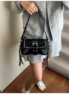 Street style shot of a black motorcycle bag with silver studs and long leather tassels