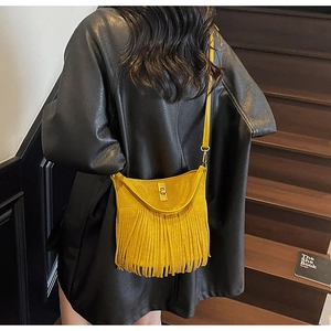 Détail d'un sac seau en daim jaune moutarde avec de longues franges et un fermoir doré