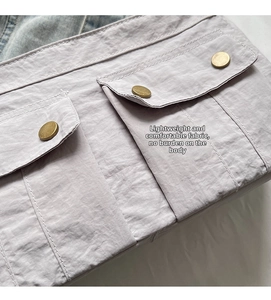 Detail of cargo bag showing lilac fabric with copper button and large utility pocket