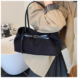 Detail of black corduroy tote bag showing ribbed texture and golden buckle detail