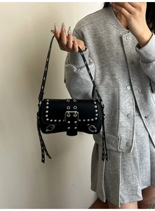 Detail of black leather punk baguette bag with silver studs on a model's shoulder