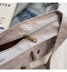 Detail of smooth metal zippers and front button flap pockets on a grey-purple nylon bag