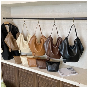 Close-up of minimalist hobo tote bags with matching zipper pouches in neutral earth tones