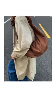 Detail of brown suede crescent hobo bag with pleated shoulder strap worn by a model