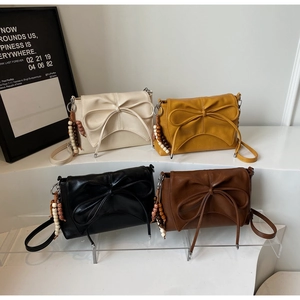 Detalle de cuatro bolsos bandolera de colores con lazos grandes y colgantes de madera