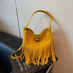 Detail of bohemian yellow suede bucket bag with long tassels and golden metal lock