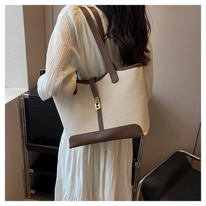 Minimalist canvas tote bag with brown leather trim and metal lock shown on a model