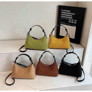Detailed arrangement of five studded crescent bags on marble steps in various colors