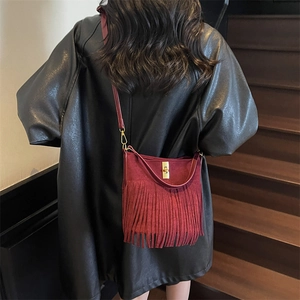 Detail of burgundy fringe crossbody bag with matte finish and gold twist-lock closure