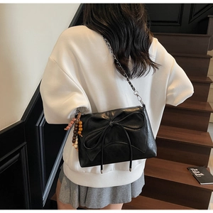 Detalle de bolso bandolera de cuero sintético negro con lazo y borla de estilo bohemio