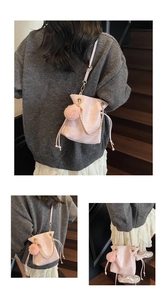 Detailed view of pink drawstring bucket bag with gold chain and pompom charm detail