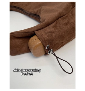 Detail of the brown suede handbag showing the side drawstring pocket and metal eyelets