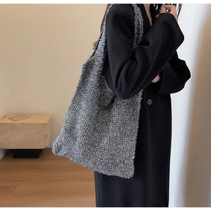 Detail view of a silver knit tote bag showing metallic texture on a minimalist coat