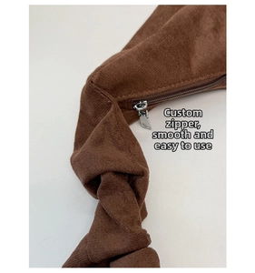 Macro view of smooth silver zipper on premium dark brown suede crescent handbag