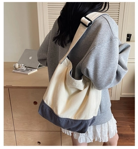 Détail du sac cabas en toile avec design bicolore et bandoulière réglable sur l'épaule