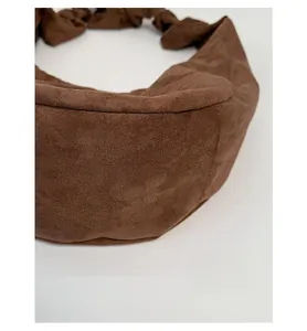 Close-up of reinforced bottom and stitching on brown suede crossbody dumpling bag