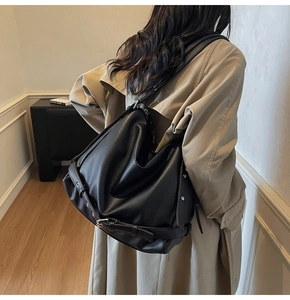 Detail showing the grainy faux leather texture and silver metal buckles on a black tote