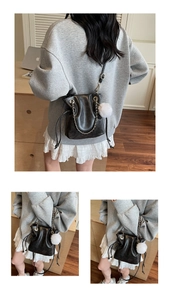 Detail view of a black leather bucket bag with silver chain strap and plush ball charm