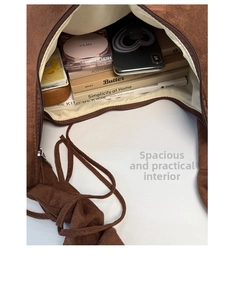 Top view of spacious brown suede hobo bag interior with books and cosmetics items
