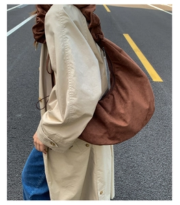 Brown velvet ruched underarm bag with pleated strap worn with a beige trench coat