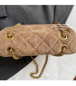 Gros plan sur le velours matelassé kaki et la chaîne en métal doré d'un petit sac carré