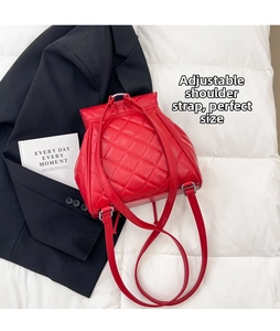 Close-up of red quilted backpack with adjustable shoulder straps and classic flap texture