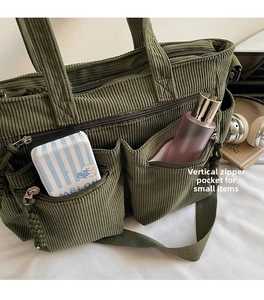 Detail of green corduroy tote bag featuring external zipper pockets for small items