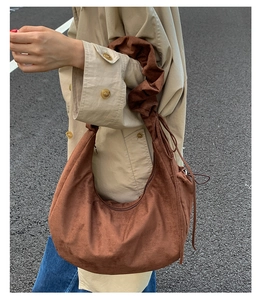 Brown suede hobo bag with unique ruched shoulder strap shown on a street style model