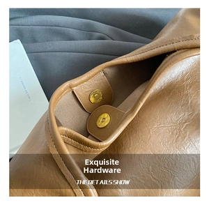 Detailed close-up of golden magnetic snap closure on brown leather bucket tote bag