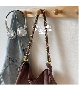 Détail du sac fourre-tout en daim marron foncé avec bandoulière chaîne sur un crochet mural