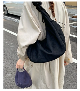 Outdoor shot of a black large capacity dumpling bag and purple cap on a model in trench coat
