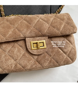 Détail du fermoir rotatif doré sur le sac à bandoulière en velours marron matelassé