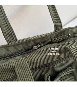 Detailed close-up of dark green corduroy fabric with smooth metal zipper and woven puller