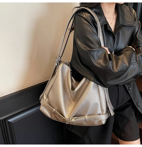 Detail of silver textured leather tote bag with metallic sheen and buckle strap decor