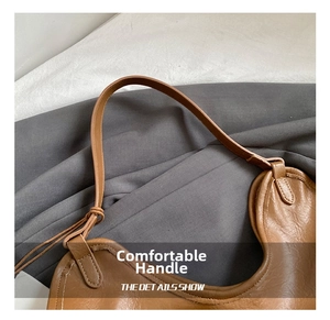 Detailed close-up of brown leather tote bag handle with refined stitching and quality texture