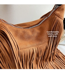 Detail of brown suede shoulder bag featuring long fringe tassels and a silver metal zipper
