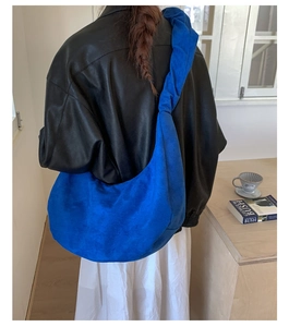 Detailed view of Klein Blue suede hobo bag with pleated shoulder strap on model