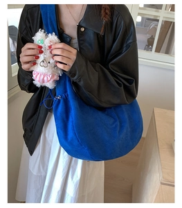 Close-up of Klein blue hobo bag in velvet texture with a cute plush rabbit charm