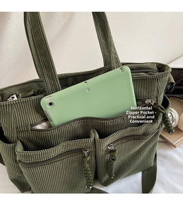 Detail of dark green corduroy tote bag featuring front zip pocket for tablet storage