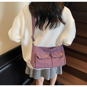 Detail view of purple nylon shoulder bag with flap pockets and gold metal buttons