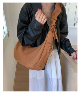 Detail of a brown suede hobo bag with a ruched shoulder strap and crescent design