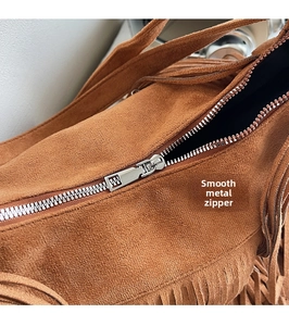 Detail of silver zipper and smooth suede texture on the brown bohemian tassel bag