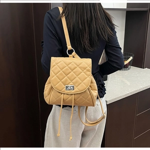 Detail of khaki quilted backpack with silver metal twist lock and PU leather texture