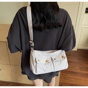 Detail of adjustable canvas strap and dual front flap pockets on a light gray crossbody bag