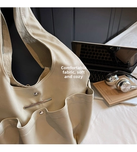 Detail of cream white faux leather tote bag with exterior pockets and silver metal accents