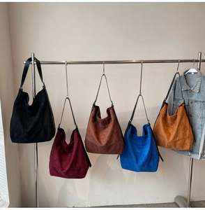 Cinq sacs seaux minimalistes de différentes couleurs suspendus à un support en métal